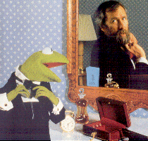 Kermit the Frog looking into mirror to tie his necktie seeing reflection of Jim Henson tying his necktie