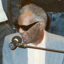 graphic image: photo of Ray Charles seated at a piano and singing into a microphone